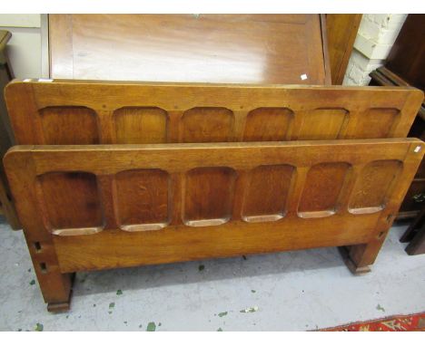 Arts and Crafts oak panelled bedstead together with a side cabinet having open shelves above two panel doors on bracket feetS