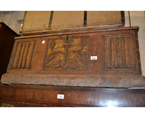 Antique oak trunk with a hinged lid above a carved panelled front and plinth base 