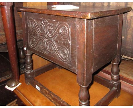 Reproduction oak box stool with a hinged lid above a carved panel front, turned supports and stretchers 