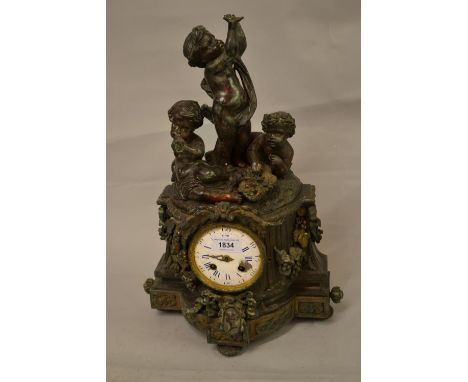 19th Century French dark patinated spelter mantel clock, the shaped floral decorated case surmounted by three figures of putt