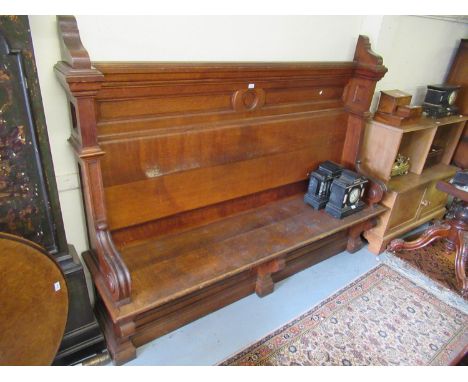 Large Victorian oak settle with panel back and seat and scroll arms on a plinth base 