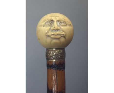 A 19th century walking stick Carved bamboo cane shaft and an ivory handle carved in the shape of the face of the moon onone s