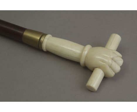 A 20th century walking stick. A carved and dyed wood shaft with a bone handle carved in the shape of a fist holding a scroll 