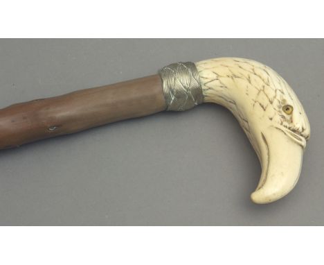 A 19th century walking stick. Carved knotted shaft and an ivory handle carved in the shape of a eagle head with glass eyes an