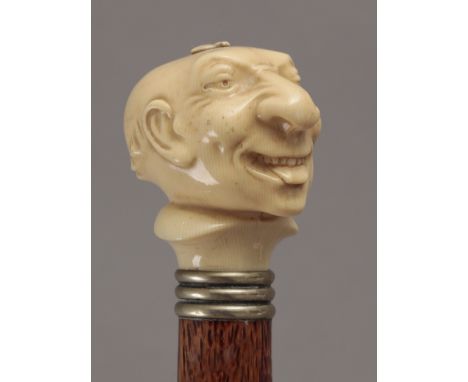 A 19th century walking stick. Carved fruitwood shaft and an ivory handle carved in the shape of a grotesque character and a m