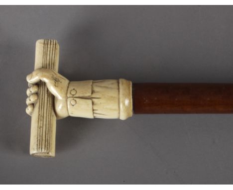 A 19th century American walking stick. Carved sherry tree wood shaft and an ivory handle carved in the shape of a fist holdin