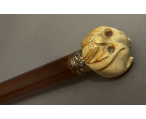 A 20th century walking stick. Carved and varnished wood shaft and an elephant ivory handle carved in the shape of the head of