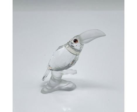 Radiant and whimsical, this multifaceted clear crystal toucan features a frosted beak and captivating pink eyes. Perched grac