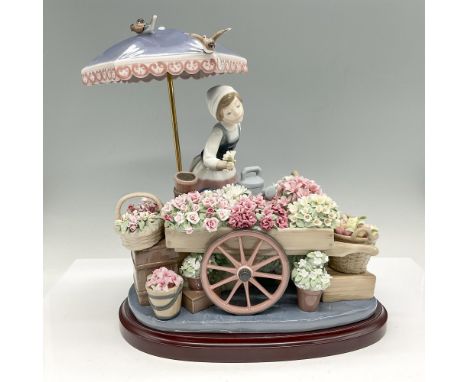 Glossy figural of young female selling a cart of colorful flowers. Standing below an umbrella with birds over head. Lladro ba