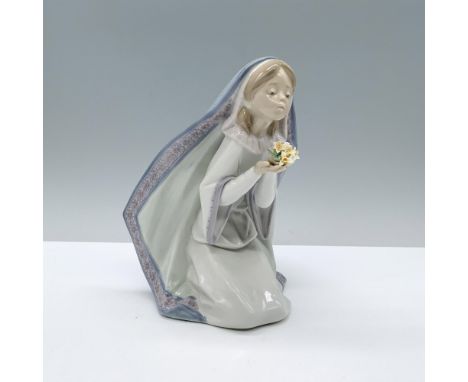 A young girl in a white robe and blue headscarf bent kneeling gracefully with a bouquet of flowers in her hand. Lladro backst