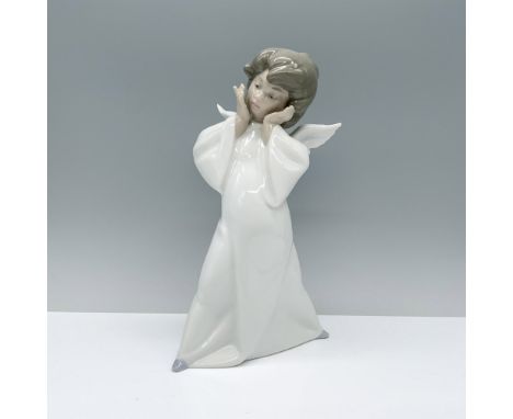 Dressed in a white robe, this angel stands with open wings and her hands almost pressed to her face. Lladro backstamp. This i