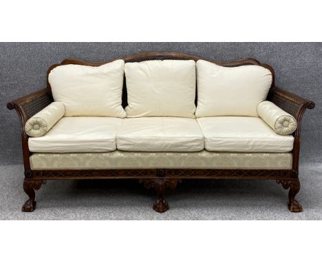 A vintage carved mahogany bergere sofa with scrolling arms, on squat cabriole legs with ball and claw feet with a rattan back