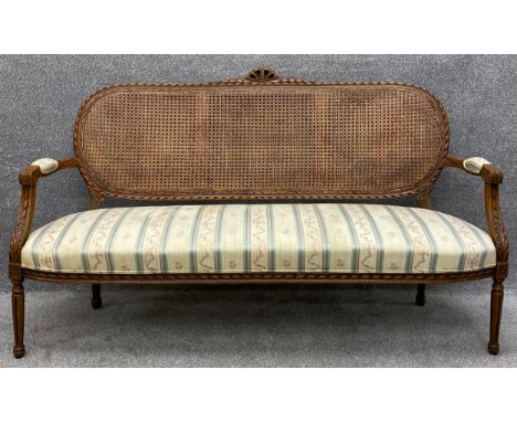 A Louis XVI style carved beech canape sofa with caned back and upholstered seat. H.99 W.168 D.66cm 