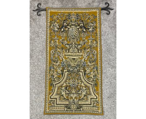 An Aubusson style linen backed wall hanging needlework tapestry with heraldic motifs and a cast iron rail, ending in Fleur de