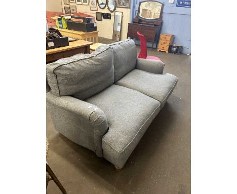 A large two seater grey upholstered sofa