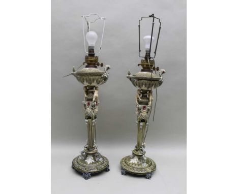 A PAIR OF CONTINENTAL CERAMIC OIL LAMPS, (converted to electricity), the reservoirs & Aladin's lamp form, the stems mask & pu