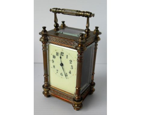 An Edwardian brass carriage clock with ivory-coloured enamel face, Arabic numerals, blind fretwork and fluted column design, 