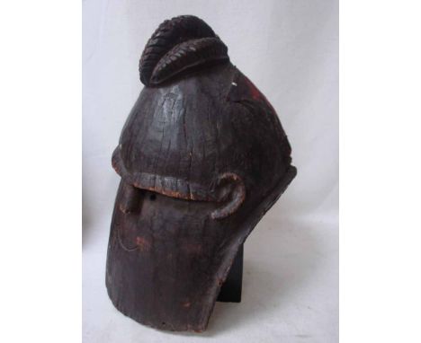 A West African Nigerian Yoruba helmet mask, carved from soft wood, elaborate cockscomb coiffure, small facial features and ea