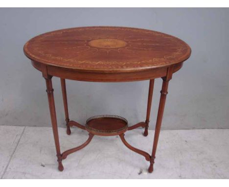 A good quality Edwardian two tier occasional table, the moulded edge oval top inlaid with central shell, surrounded by ribbon