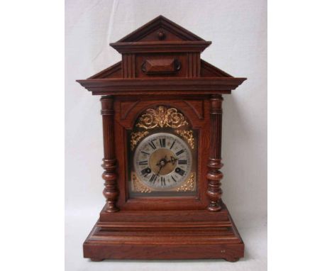 A Junghans eight day mantle clock, housed in an oak architectural style case, arch top brass face decorated with spandrels, s