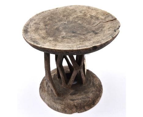 An African wooden stool,  carved from a section of tree trunk, with shallow cup shaped top and base, carved central supportin