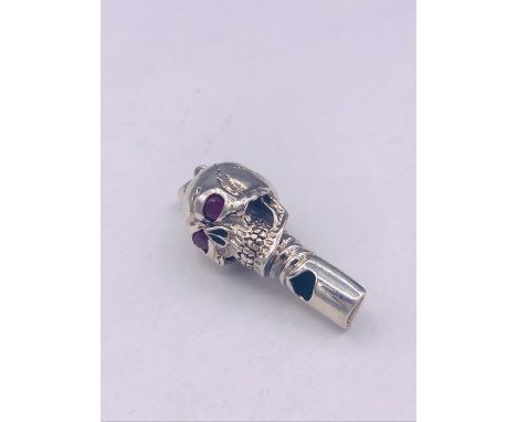 An unusual silver skull shaped whistle with ruby eyes