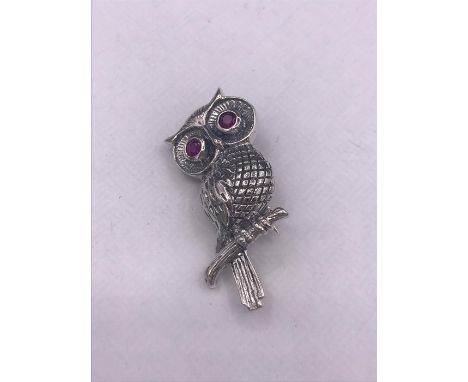 A silver owl brooch with ruby eyes