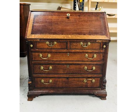 A George III oak crossbanded bureau, the fall enclosing a stepped interior with serpentine drawers and recesses, above two sh