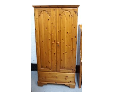 DUCAL WAXED PINE WARDROBEwith a moulded top above two panelled doors, one with an interior mirror, above a frieze drawer, sta