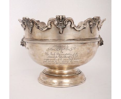 A George IV silver Monteith. Of heavy gauge, the scalloped rim with relief scroll border, over lion mask handles and circular