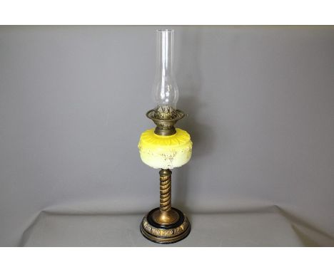 A Victorian acid yellow oil lamp; the lamp having a bright yellow oil reservoir, on black and gilt base, glass chimney, appro