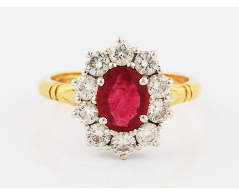 An 18ct yellow gold ruby and diamond cluster ring, set with a central oval cut ruby, measuring approx. 8x6mm, surrounded by a