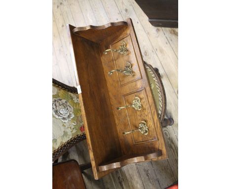 An oak hall shelf with brass coat hooks