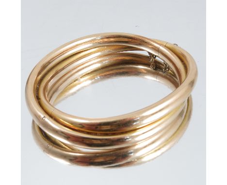 A gold hinged bangle, stamped '15ct' to the catch, of double crossover design, circa 1910, internal diameter 5.6cm, 21g gross