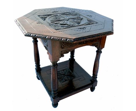 An octagonal shaped oak centre table, with carved central panel and similar shelf below, width 30ins