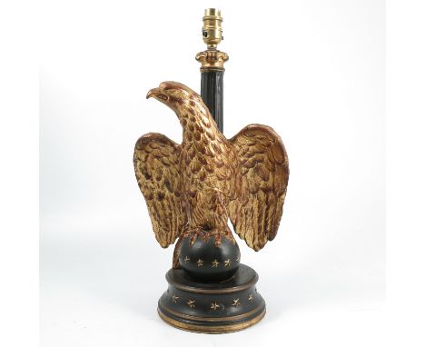 A metal table lamp, formed as a column with an eagle in front perched on a ball decorated with stars, the circular base also 