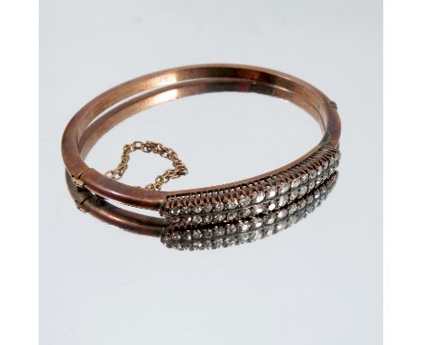 A late Victorian diamond set hinged bangle, apparently unmarked, the thirty six small old cut diamonds set in two rows, inter