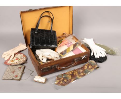 A small vintage leather suitcase containing ladies evening gloves, purses and handbags etc.
