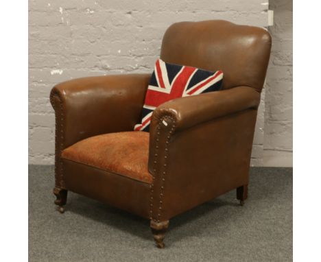 A 1950s brown leatherette club chair on carved mahogany feet.Condition report intended as a guide only.Minor tear to the leat