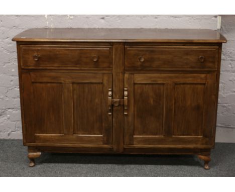 An Ercol style carved and panelled oak sideboard, raised on squat cabriole supports