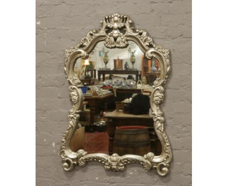 A large ornate silvered frame wall mirror, 116cm x 77cm.