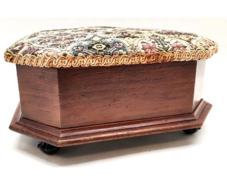 Upholstered mahogany footstool with ceramic feet. Reupholstered top which lifts up. Measures 35 x 30 x 15cm. 