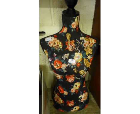 A collection of costume brooches on a mannequin 