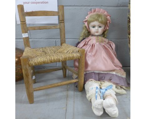 A large antique reproduction bisque head character doll on woven wooden chair, 76cm **PLEASE NOTE THIS LOT IS NOT ELIGIBLE FO