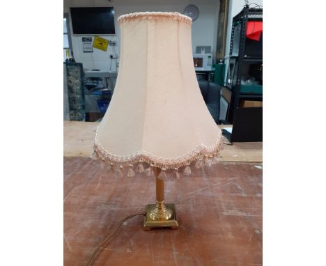 A brass table lamp with cream fringed shade standing 60cm high and in good condition.