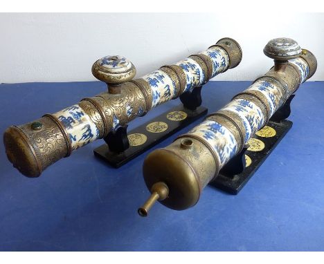 An unusual pair of Chinese blue and white porcelain and metal-mounted antique-style ceremonial pipes on ebonised inlaid stand