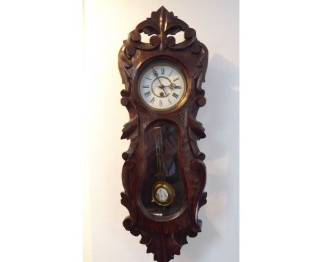 An early 20th century wall-hanging clock with foliate carved case; the white-enamel dial with Roman numerals, with original p
