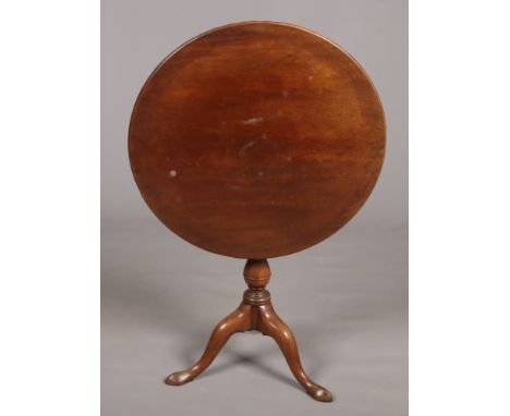 A George III mahogany snap top tripod table. Rotating on a bird cage mechanism and raised on plain scroll supports, 67cm diam