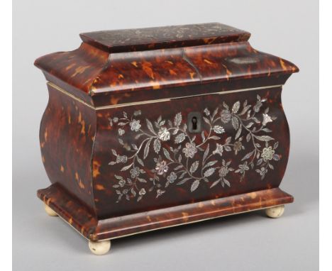 A Regency tortoiseshell tea caddy of sarcophagus form. Profusely inlaid to the front and top with mother of pearl to depict s