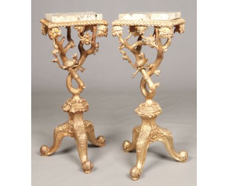 A pair of George II style marble top giltwood torchere stands. With gadrooned rims, of rustic branch form surmounted with bir